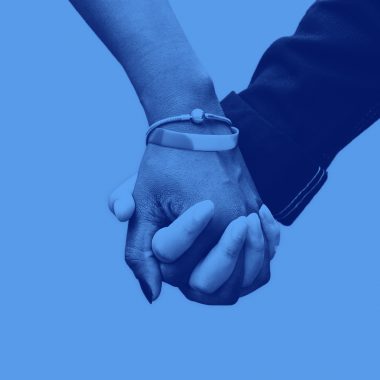 image of two hands holding each other on a blue blackground.