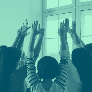 group of people with hands raised together, green filter