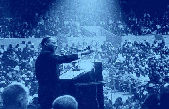 photo of Martin Luther King Jr Speaking at a podium in front of crowd, blue filter.