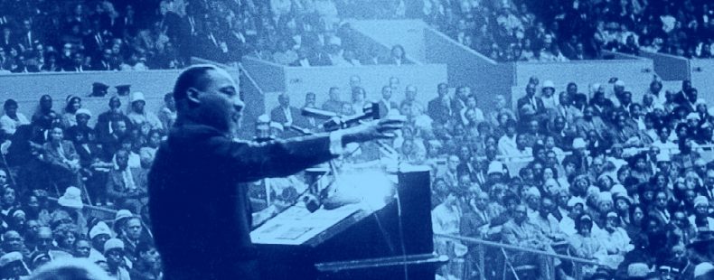 photo of Martin Luther King Jr Speaking at a podium in front of crowd, blue filter.