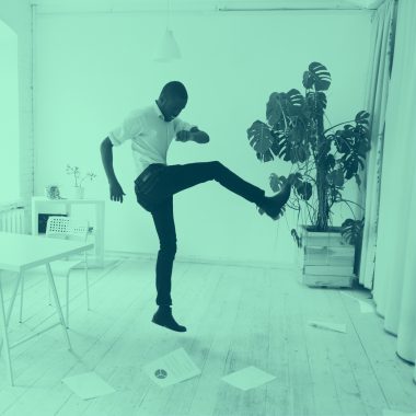 man in office stomping on and kicking at papers on the ground, green filter.