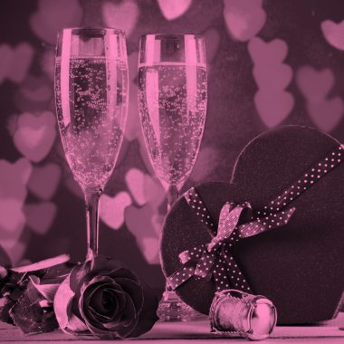 2 champagne glasses and a heart-shaped box of chocolates, pink filter