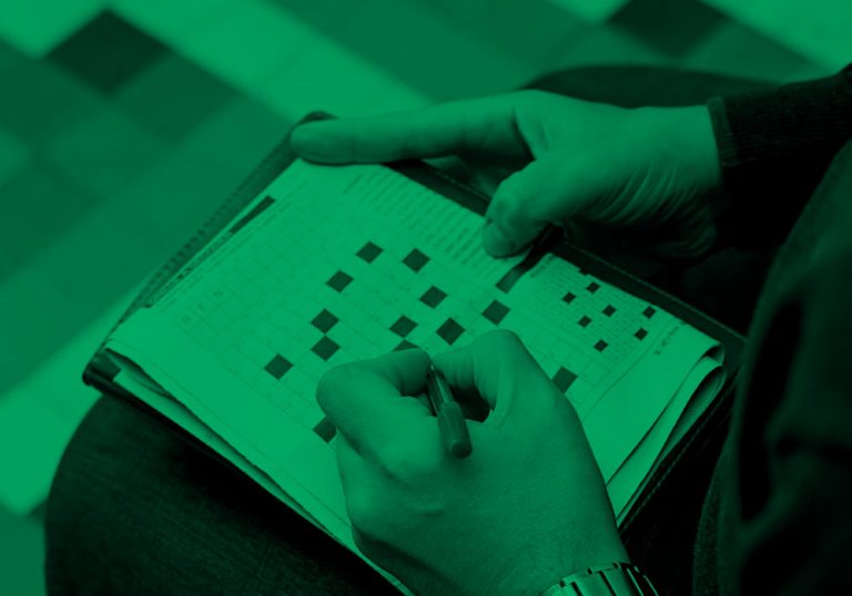 close-up of someone working on a crossword puzzle, green filter.