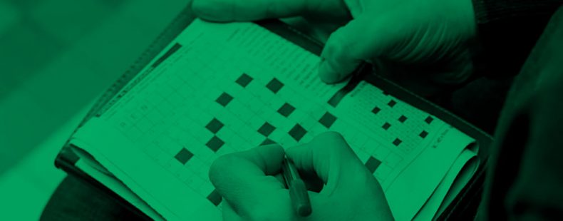 close-up of someone working on a crossword puzzle, green filter.