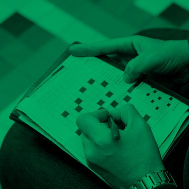 close-up of someone working on a crossword puzzle, green filter.