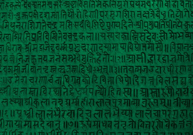 Background with ancient sanskrit text etched into a stone tablet, green filter.