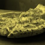 A whole pizza pie with one slice cut and ready to serve