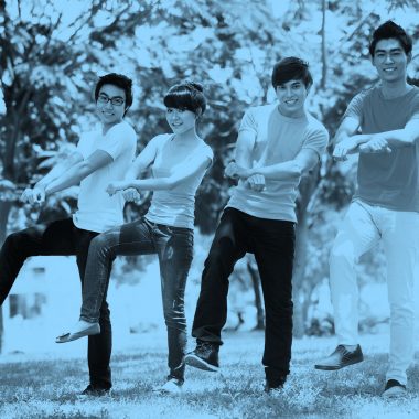 Photo of four young friends doing the "Gangnam Style" dance, blue filter.