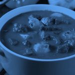 a pot of stew on a dining table, blue filter.