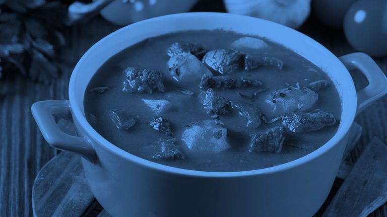 a pot of stew on a dining table, blue filter.