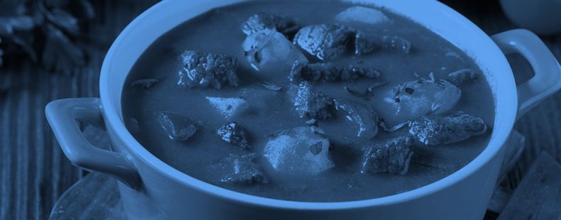 a pot of stew on a dining table, blue filter.