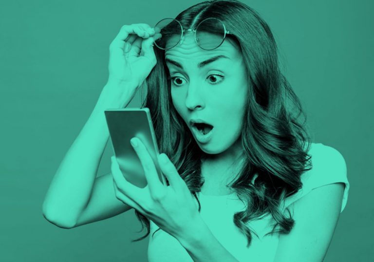 image of shocked woman looking at her phone, teal filter.