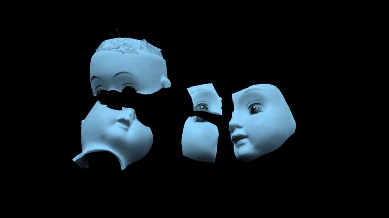 blue filtered image of broken pieces of porcelain doll's head, on black background.