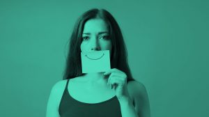 woman holding post-it note with smiley face