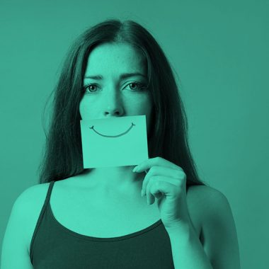 woman holding post-it note with smiley face