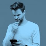 man puzzling over game on his phone, blue filter.