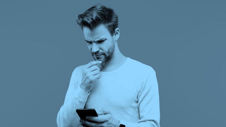 man puzzling over game on his phone, blue filter.