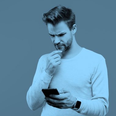 man puzzling over game on his phone, blue filter.