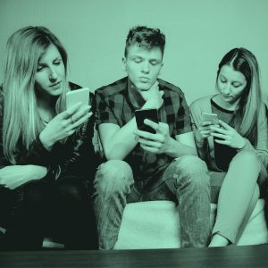 group of young adults on couch with phones in hand