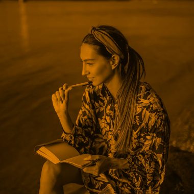 woman writing at the lake, orange filter